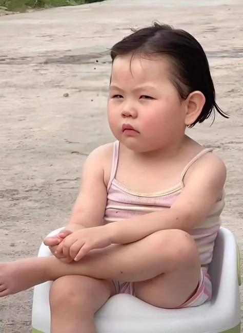 bé gái ngồi ghế nhựa biểu cảm hài hước