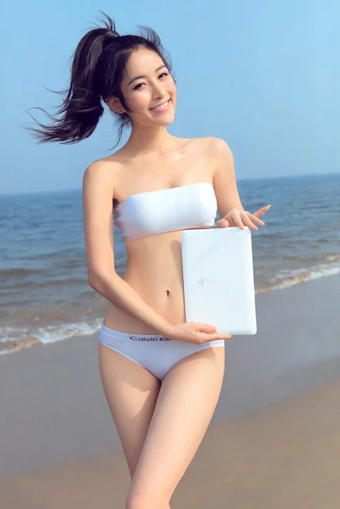 Người mẫu bikini dễ thương khoe dáng cùng máy tính bên bờ biển