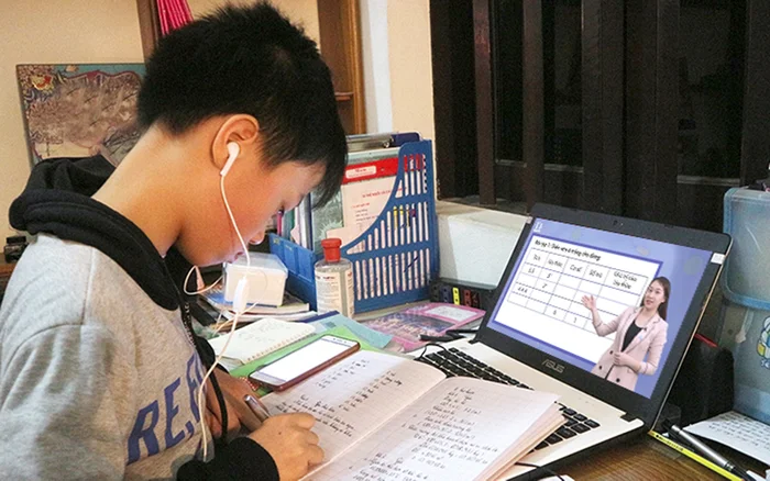Học sinh nam đeo tai nghe đang học tập trực tuyến trên máy tính