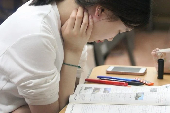 Nữ sinh học tập chăm chú đọc sách chống cằm suy nghĩ