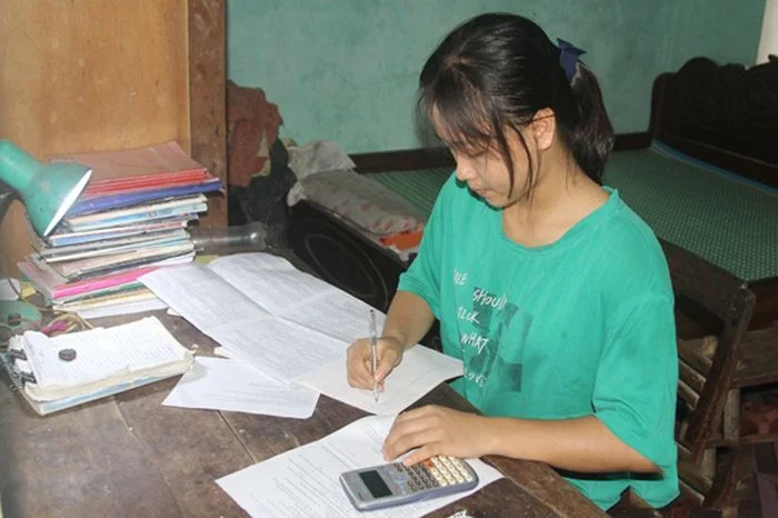 Nữ sinh học tập chăm chỉ làm bài tập với máy tính cầm tay trên bàn học tại nhà