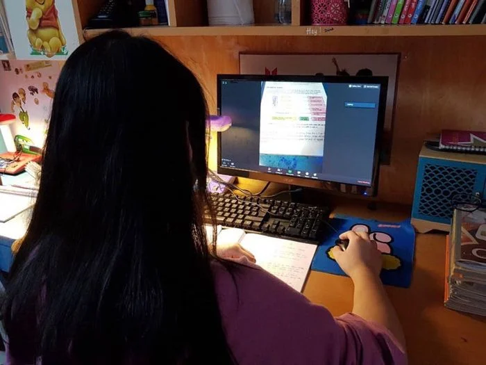 Nữ sinh đang học tập trực tuyến trên máy tính tại bàn học