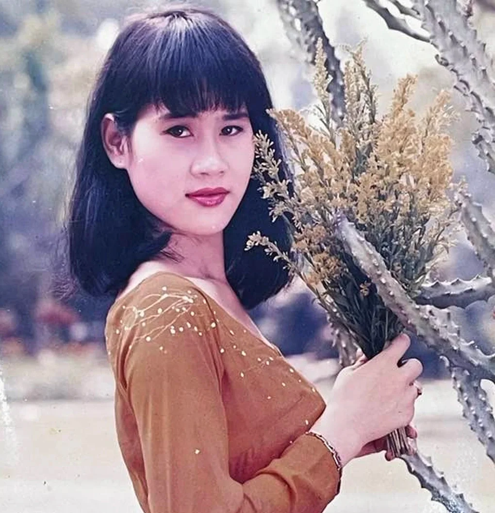 Ảnh người mẫu Việt Nam mặc áo nâu nắm bó hoa khô ngoài trời, phong cách cổ điển.